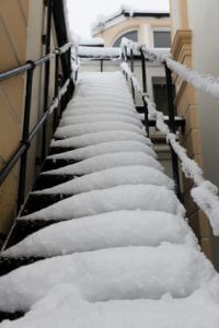 A long staircase covered in snow next to a railing.