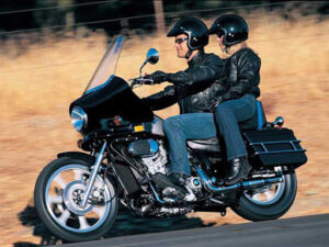 Two people on a motorcycle riding down the road.